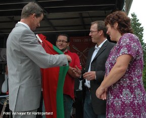 Bürgermeister Rolf Claussen überreicht die Wittmund-Fahne an die Geschwister Siuts